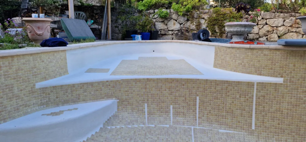 Pose précise des petites tesselles dans la piscine